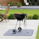 Barbecue à charbon sur tapis de protection posé sur une terrasse en bois