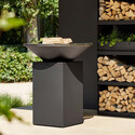 Brasero OFYR noir Classic 85 sur terrasse devant une armoire de bois