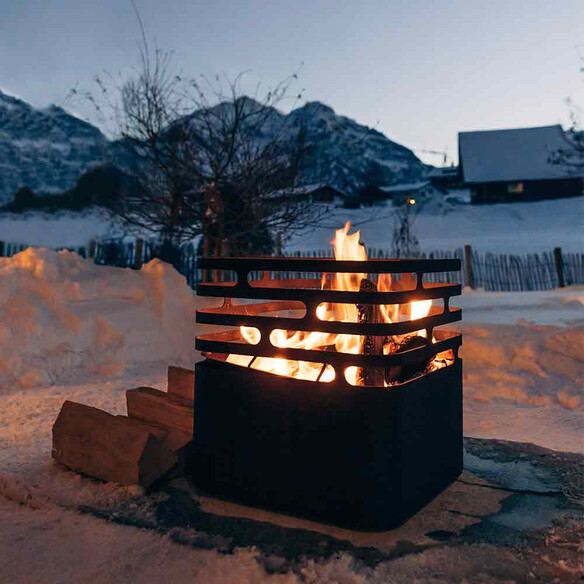 Brasero Cube Hofats noir allumé et posé dans la neige