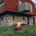 Brasero corten Cube Höfats enflammé installé sur une dalle entourée d'herbes