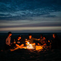 Groupes de personnes éclairées par les flammes du Brasero corten Cube Höfats pendant la nuit