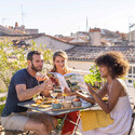 Femme montrant à ses amis 1 recette dans le livre Cuisiner à la plancha toute l'année par ENO et Delphine Lebrun