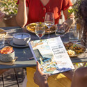 Femme tenant le livre de recettes Cuisiner à la plancha toute l'année ENO