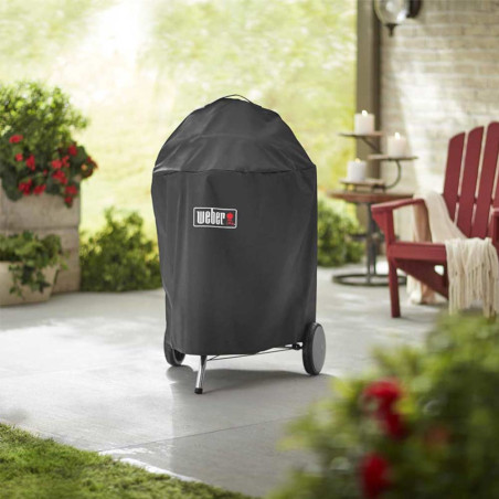 Photo d'ambiance d'un barbecue charbon Weber recouvert par la housse premium