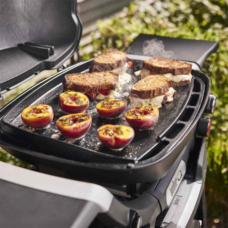Aliments en train de cuire sur une plancha intégrale en fonte émaillée - barbecue gaz Q 1000 N Weber Aliments en train de cuire sur une plancha intégrale en fonte émaillée - barbecue gaz Q 1000 N Weber