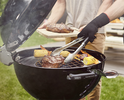 Pièces de viande et épi de maïs en cuisson sur un barbecue charbon