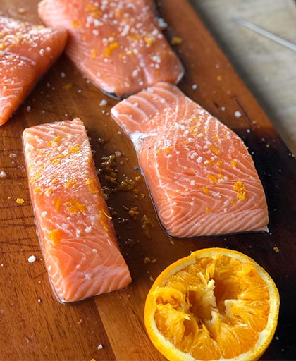 Salage à sec d'un saumon sur une planche de bois