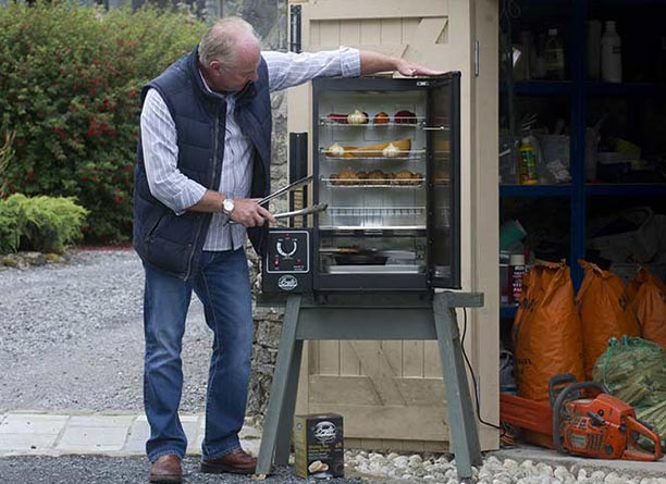 Homme cuisinant dans le fumoir Original Smoker Bradley 4 étages