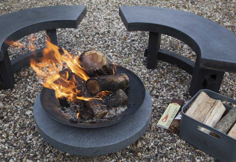 Banc en pierre installé autour d'un brasero en fonte