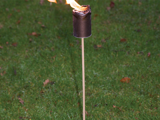 Flambeau de jardin en combustion planté dans l'herbe