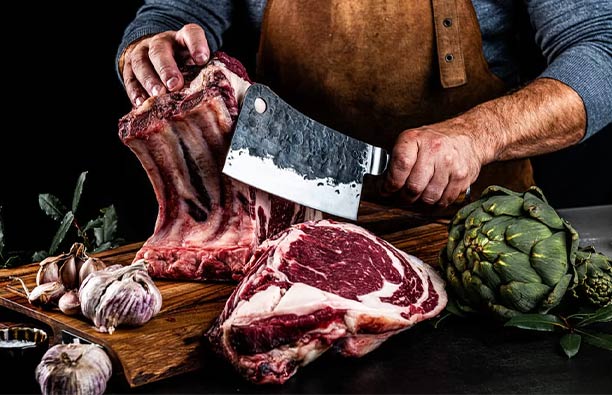 Homme utilisant le couperet Forged Olive pour une pièce de boeuf