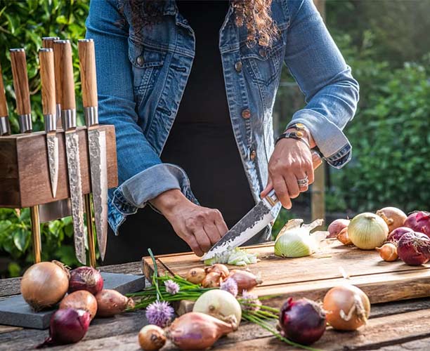 Femme coupant des légumes avec le couteau du chef Forged Olive 16 cm