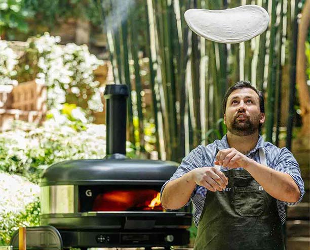 Préparation d'une pizza près du four à pizza Gozney Dome XL Gen 2 noir