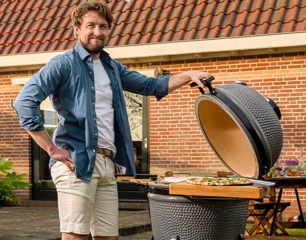 Cuisson d'une pizza sur la pierre à pizza, posé sur un kamado Grill Guru dans un jardin