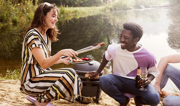 Barbecue kamado posé sur la place avec 2 personnes dégustant des aliments cuits au barbecue