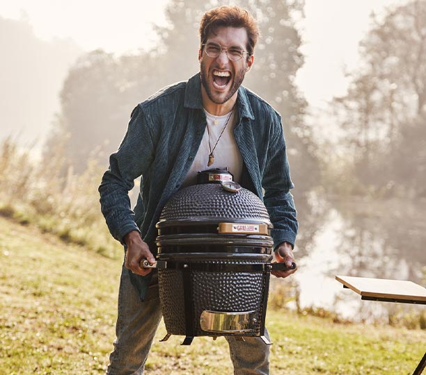 Homme portant le kamado Original Compact Grill Guru, barbecue léger