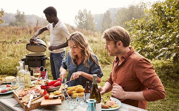 Personnes mangeant autour d'une table un repas préparé un kamado