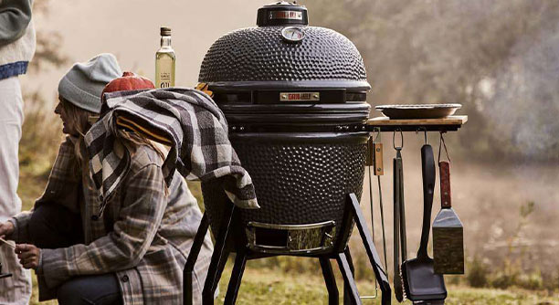 Barebcue kamado Original Large dans un jardin avec des accessoires accrochés