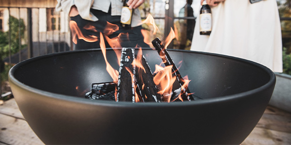 Zoom sur la demi sphère du brasero barbecue Bowl avec des bûches enflammées