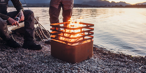 Brasero corten Cube Höfats posé sur des graviers près de l'eau