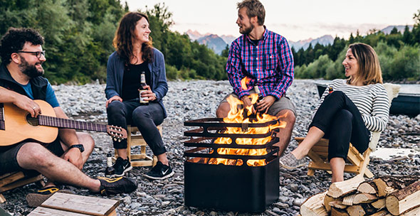 Groupe de personnes entourant le brasero Cube Höfats noir avec des flammes