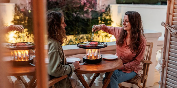 2 femmes utilisant le barbecue de table Circle 35 Höfats sur un balcon