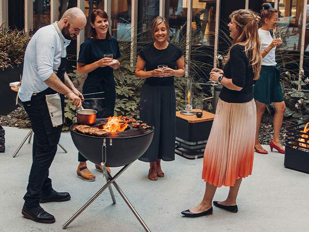 Brasero Bowl 70 sur trépied en inox Höfats avec des personnes préparant un repas