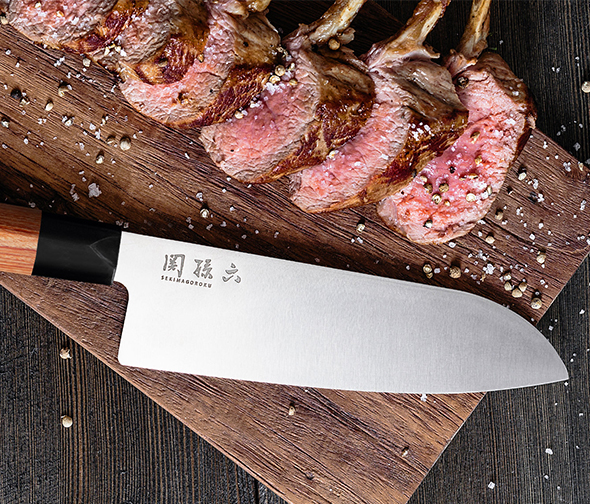 Couteau KAI posé sur une planche à découper avec des morceaux de viande