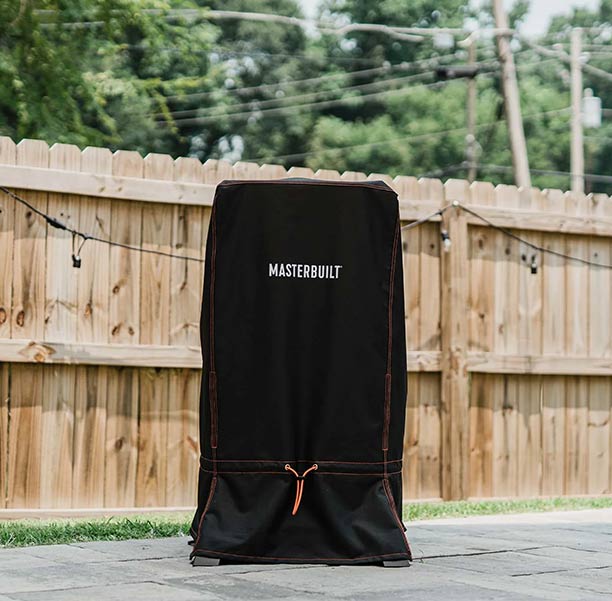 Fumoir connecté 710 Masterbuilt et sa housse de protection sur une terrasse
