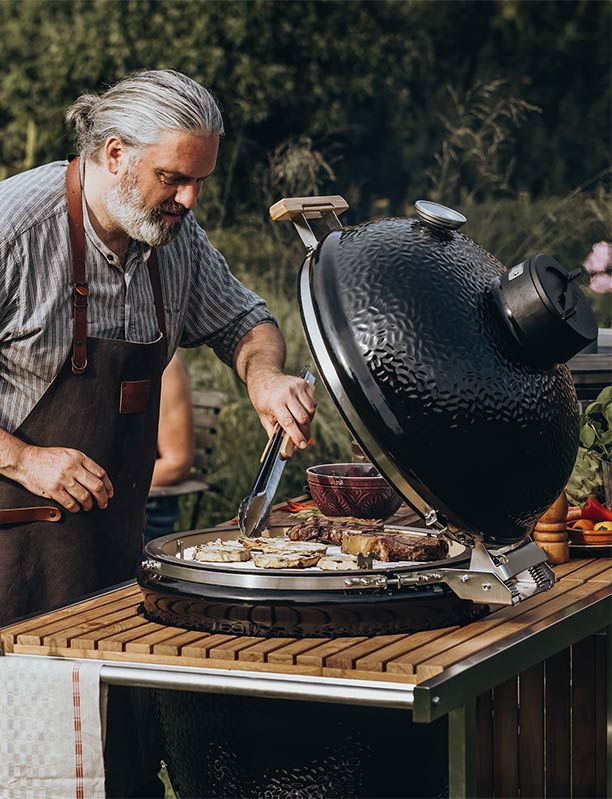 Homme qui cuisine sur le barbecue kamado Guru Classic PRO 2.0 Monolith encastré