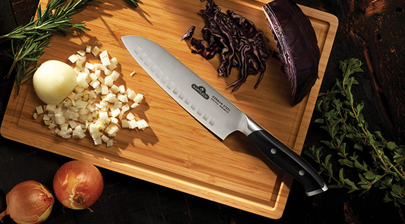 Couteau Santoku posé sur planche à découper avec aliments taillés