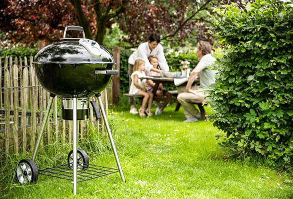 Barbecue charbon Rodeo 57 cm installé dans un jardin familial