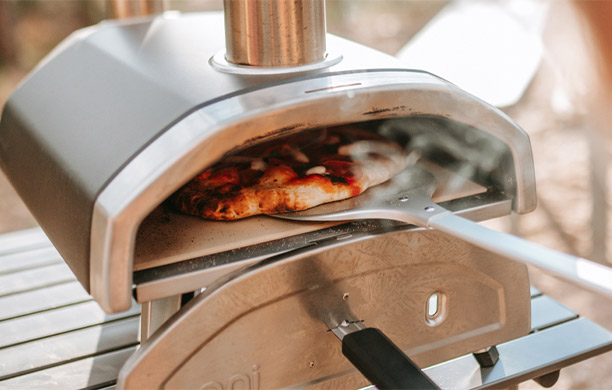 Manipulation d'une pizza avec la pelle à pizza tournante dans un four à pizza Ooni