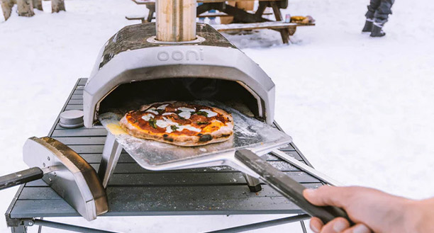 Retrait d'une pizza du four à pizza Ooni avec la pelle en aluminium