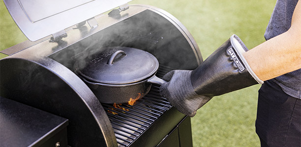 Personne manipulant un plat chaud avec les gants de protection barbecue Pit Boss en néoprène et revêtement nitrile