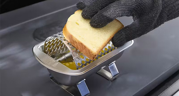 Rouleau à beurre Weber en inox posé sur une plancha