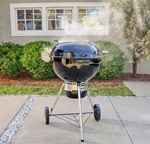 Barbecue à charbon Weber Master-Touch Premium 5770 noir 57 cm avec couvercle fermé sur terrasse.
