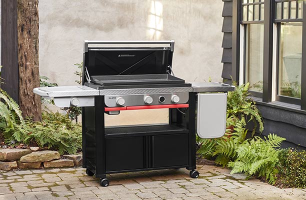 Plancha Weber Slate 76 cm avec réchaud latéral sur chariot avec le couvercle ouvert sur une terrasse